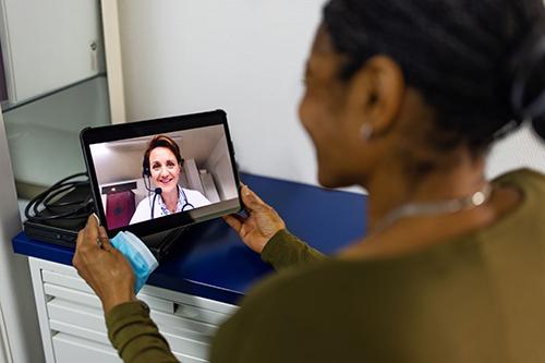 一名妇女在平板电脑上与医疗专业人员交谈