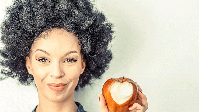 灰白头发的女人吃着心形的苹果