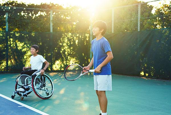 少年坐在轮椅上打网球